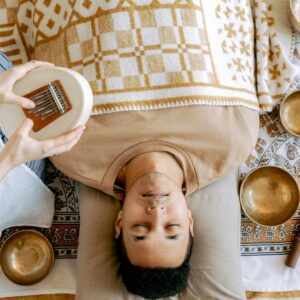 A serene sound bath session featuring a man relaxing with a kalimba and singing bowls.