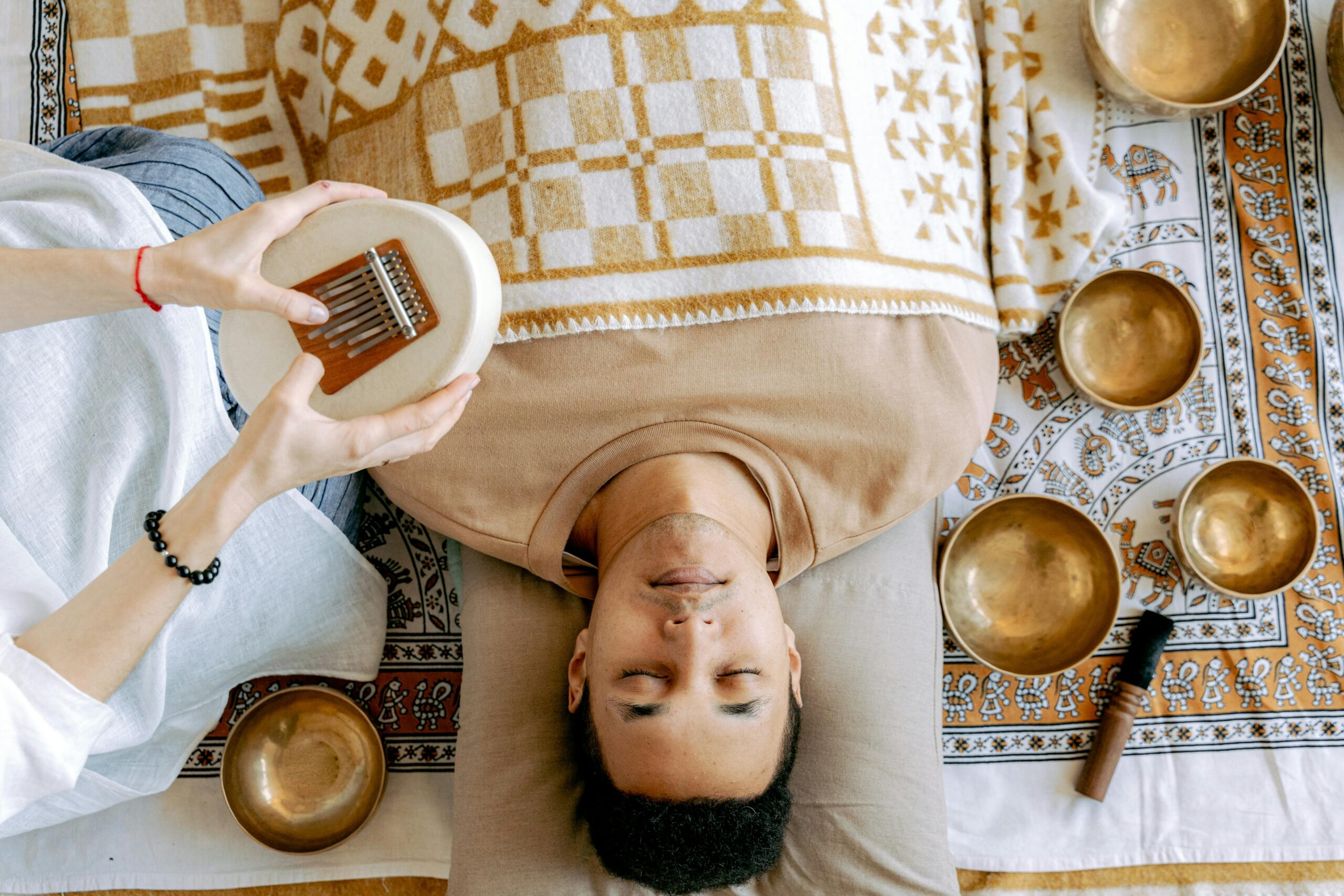 A serene sound bath session featuring a man relaxing with a kalimba and singing bowls.