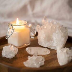 A serene still life of a lit candle surrounded by crystals on a wooden tray, perfect for relaxation.